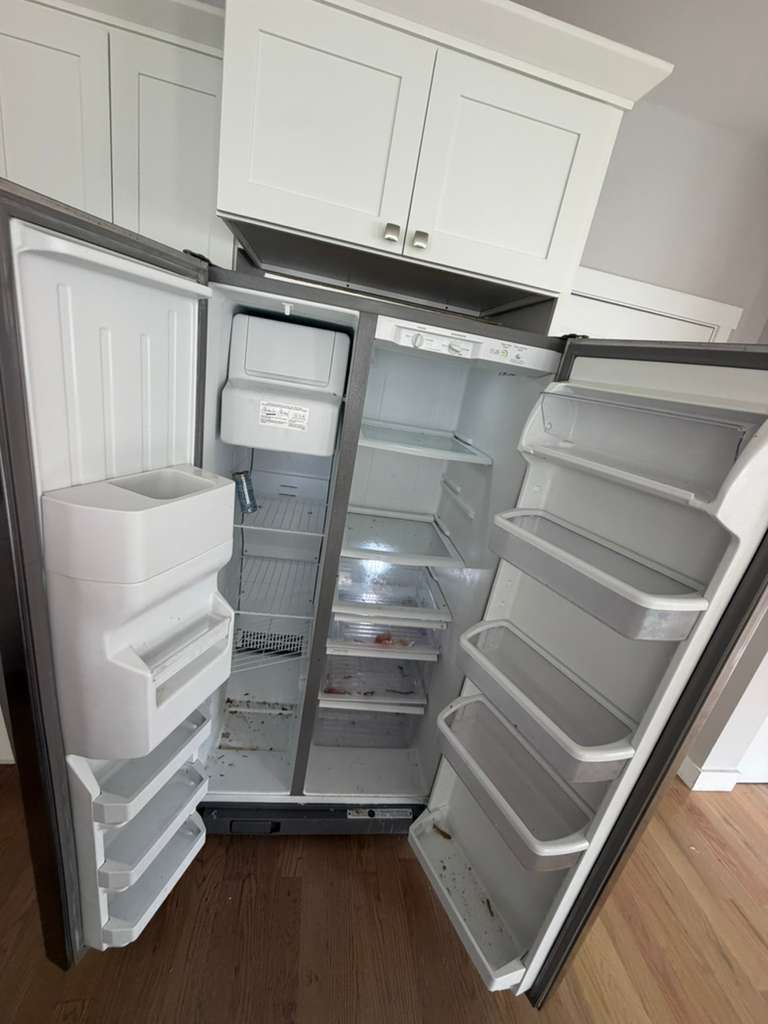 Refrigerator interior before cleaning, with spills and crumbs on the shelves